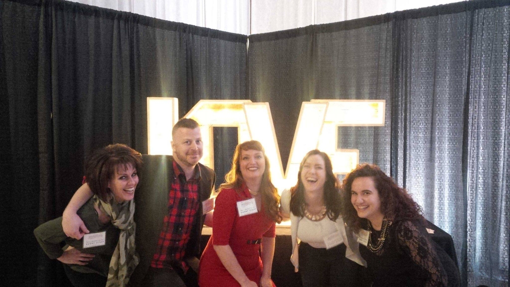 Wedding Shows Windsor Staff posing in front of the big LOVE selfie wall!